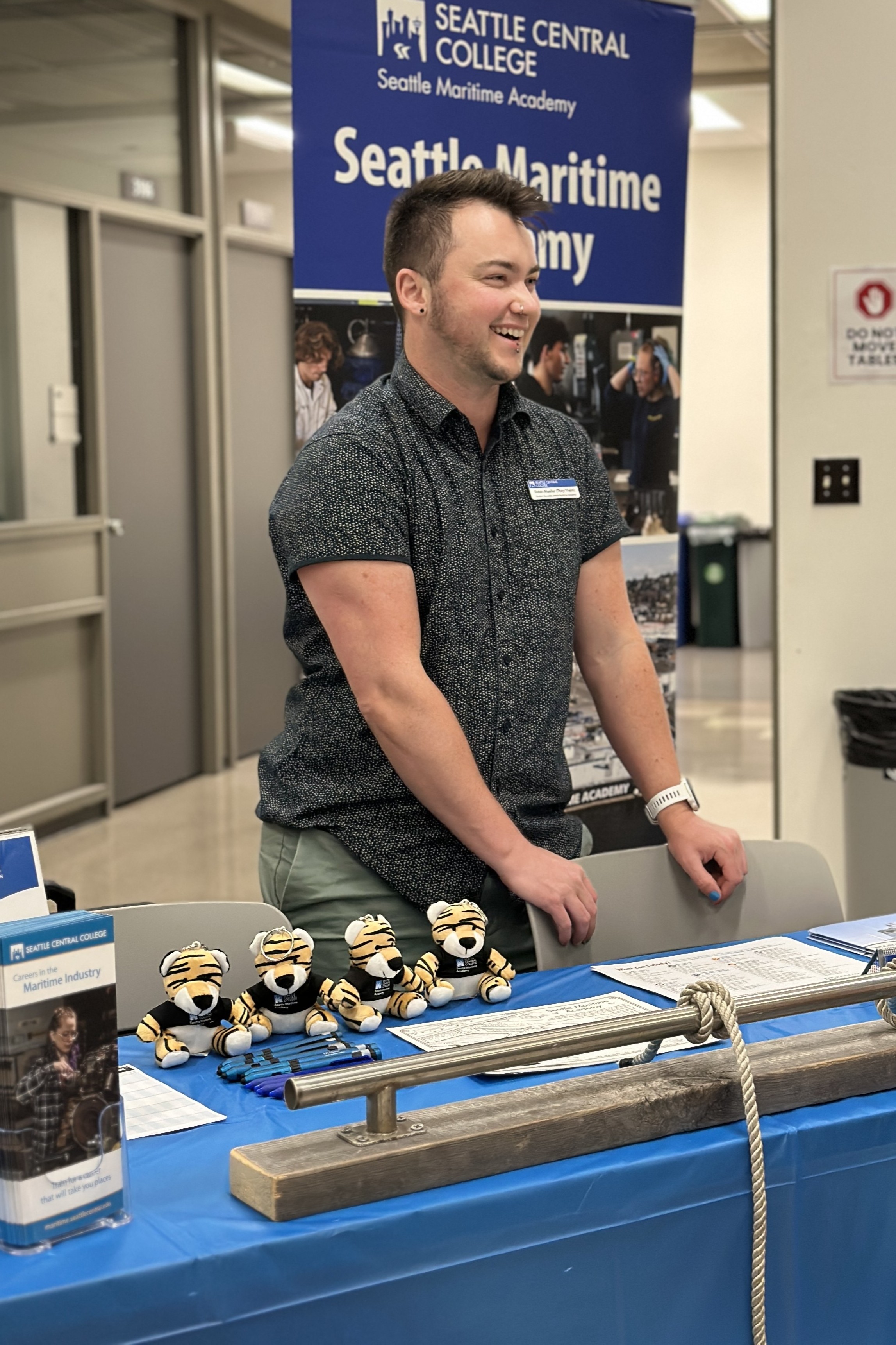 Robin Mueller smiling and standing behind their SMA outreach table at a career fair